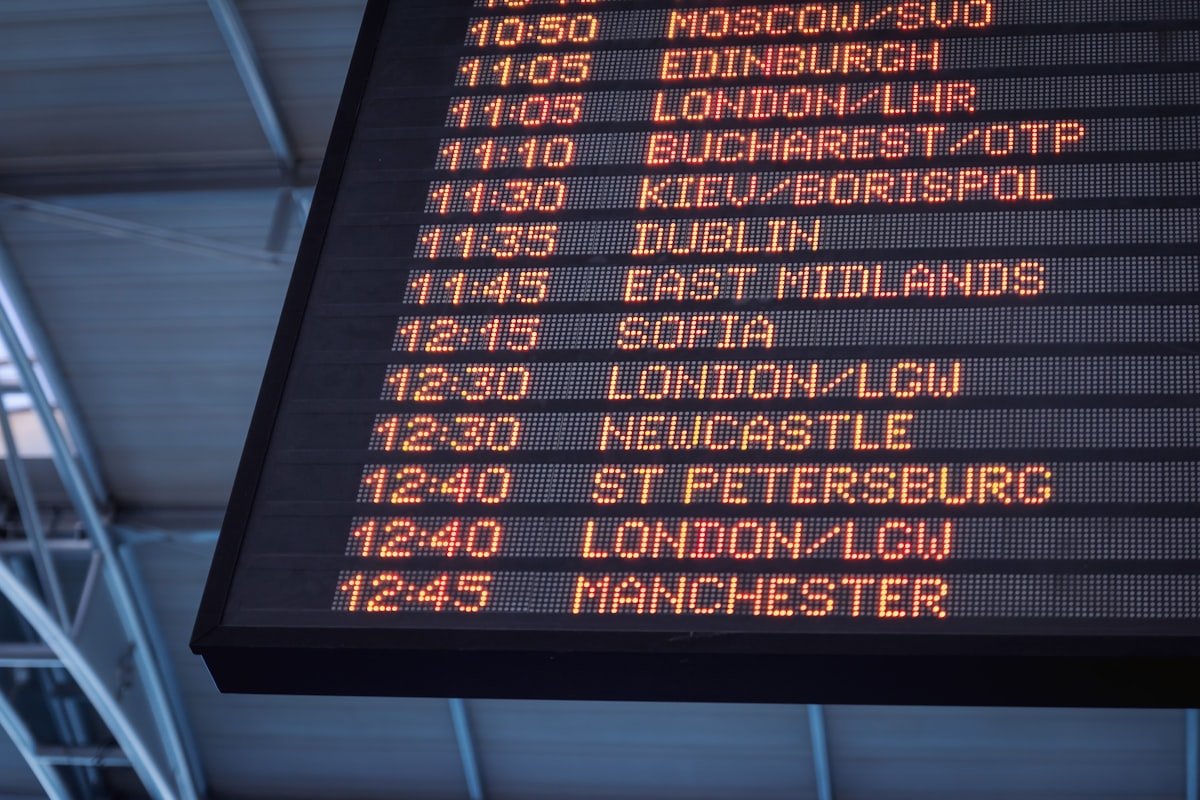 An airport split-flap departure board listing flights to London, Edinburgh, Manchester, Dublin, and other cities