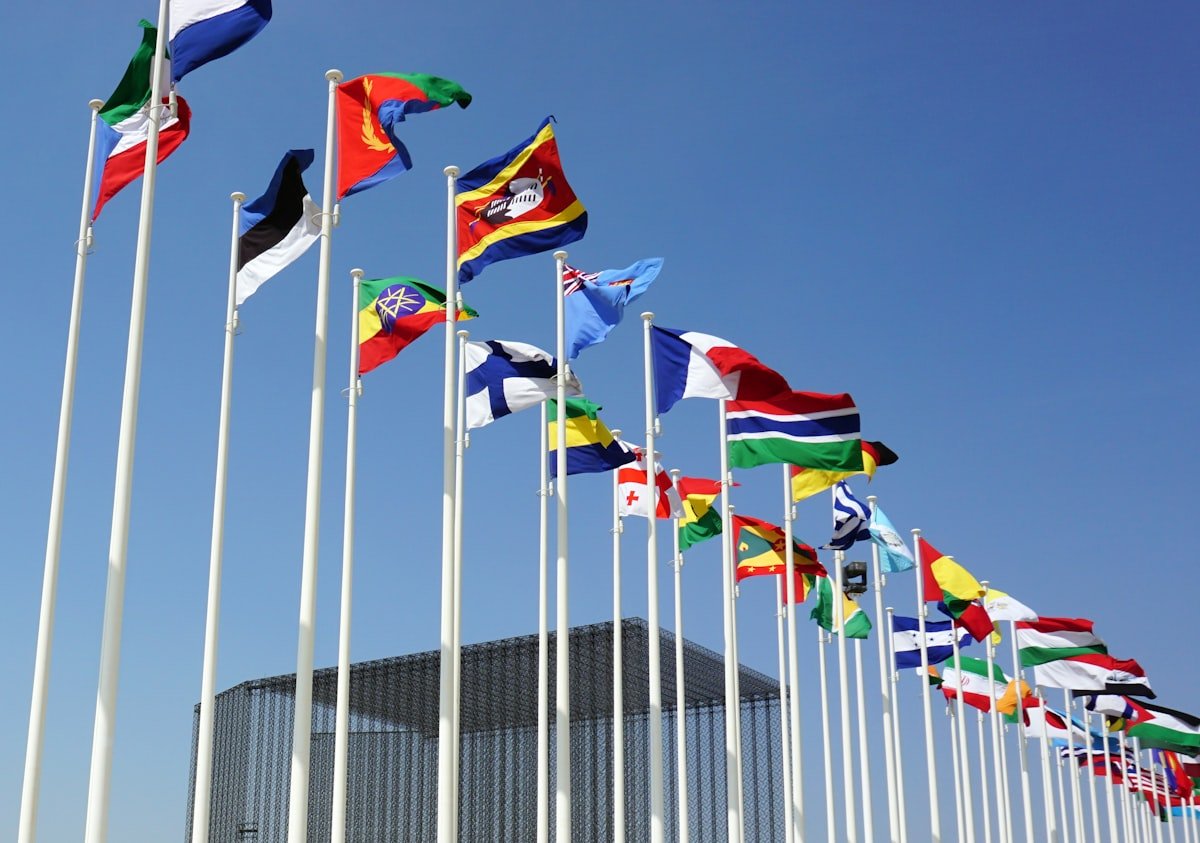 Multiple national flags flying against a blue sky